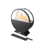 A sleek black round Subesta bioethanol fire pit with a glass screen displays warm flames, suitable for indoor or outdoor use.