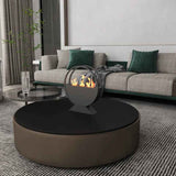 A NatureScape Living black round bioethanol fireplace displays dancing flames on a coffee table in a stylish living room.