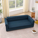 A navy blue elegant modern oversized linen fabric dog sofa bed with a tufted back and studded trim, on a rug in a sunlit room.