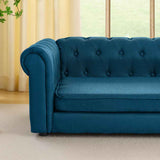 Stylish teal button-tufted elevated dog bed sofa with rolled arms and textured fabric by a bright window.