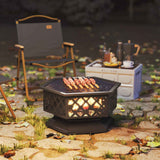An 18-inch metal wood-burning Fire Pit with Cooking Grate has skewers sizzling over flames in a cozy outdoor evening scene.