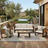 NatureScape Living's Outdoor 3 Seater Sofa, a 4-piece aluminum patio set with beige cushions and wood accents on a deck.