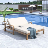 A TREXM Farmhouse Wooden Outdoor Sunbed with beige cushions and a blue blanket rests by a tiled poolside patio.