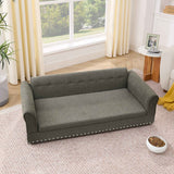 Elegant oversized dark grey linen dog sofa bed with tufted backrest, armrests, and decorative studs on a patterned rug.