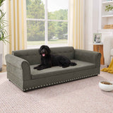 A black dog lounges contentedly on an elegant dark grey linen Oversized Pet Sofa, an elevated dog bed with nailhead trim.