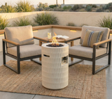 NatureScape Living's 26" Propane Patio Fire Pit, a textured cream cylinder with flames, between two outdoor chairs on a patio rug.