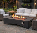 A dark gray 56" Rectangular Gas Fire Pit Table with flames illuminates a patio with white-cushioned wicker outdoor furniture.