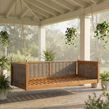 A TOPMAX Acacia Wood Swing Bed with natural wood slats and wicker panels hangs from ropes on a serene outdoor porch.