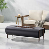 The dark grey VERNON Rectangle Fire Pit, with its wooden legs and lava rock interior, is on a light patio beside an outdoor sofa.