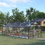 A NatureScape Living aluminum polycarbonate walk-in greenhouse kit, filled with plants in a sunny backyard next to a treehouse.