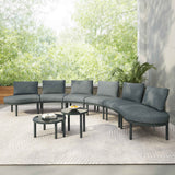 A grey TOPMAX 8-Piece Half Moon Wicker Rattan Sofa Set, with two round tables, on a patio rug amidst lush greenery.