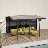 A NatureScape Living 12x10 polycarbonate pergola, grey-framed with a translucent roof, shelters a green sectional sofa on a wooden deck.