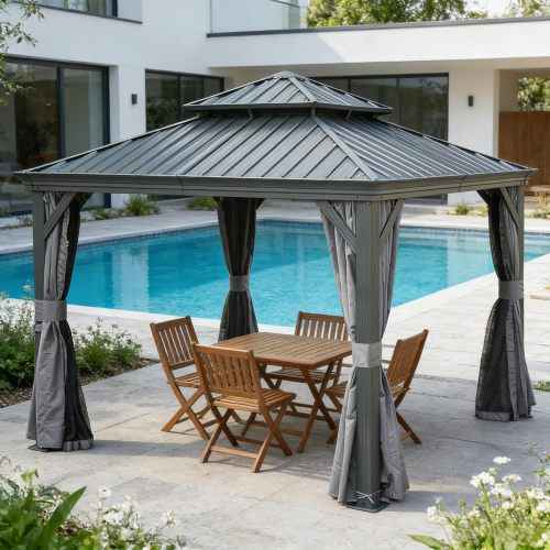 A NatureScape Living 13x13 Hardtop Gazebo with a grey galvanized steel roof, curtains, and wooden patio furniture by a pool.