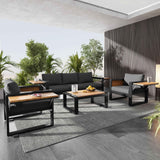 NatureScape Living's 4-piece dark grey aluminum frame outdoor sofa set with wood accents on a modern patio.