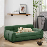 A fluffy white dog lies on a comfortable green dog sofa bed with backrest and armrests, set in a bright living room.