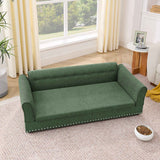 This elegant, oversized green linen dog sofa bed features a tufted back and silver nailhead trim, placed on a cozy rug.