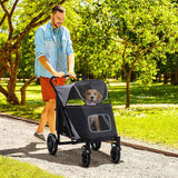 A man pushes a gray Dog Stroller with a light brown dog happily peeking out of the mesh window while walking through a sunny park.