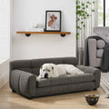 A white dog relaxes on a dark gray, tufted Elegant & Comfortable Large Dog Sofa Bed by NatureScape Living in a cozy room.