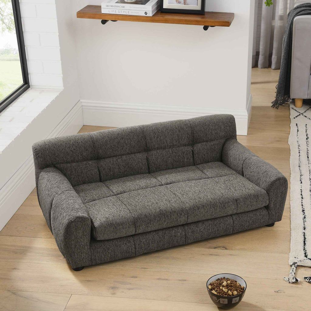 NatureScape Living's elegant dark gray tufted large dog sofa bed sits on a light wooden floor, with a pet food bowl nearby.