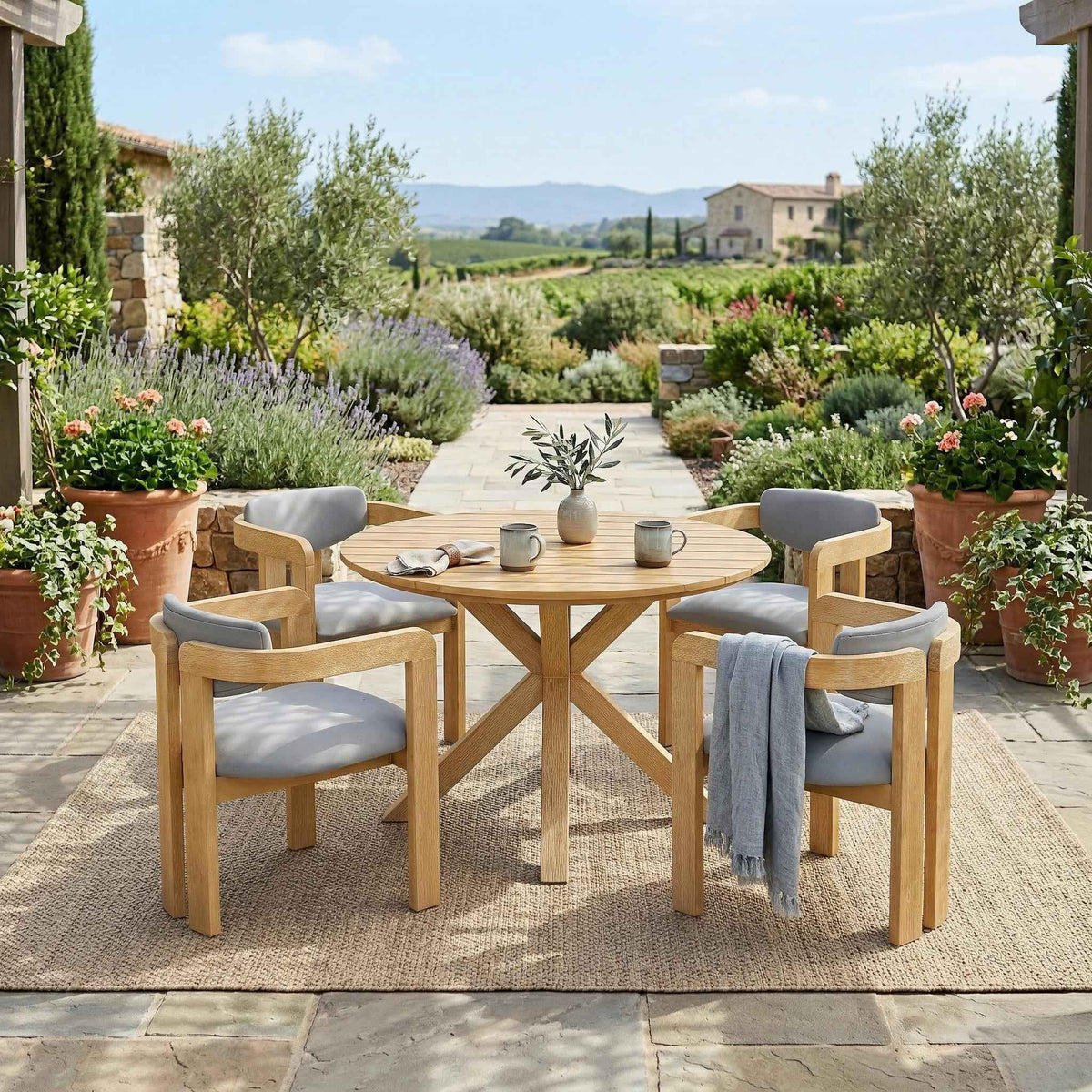 A NatureScape Living 5-piece acacia wood round patio dining set with gray cushions on a sunlit outdoor patio.