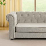 An elegant rectangular elevated dog bed, a light grey tufted pet sofa with a rolled arm, rests on a light carpet.