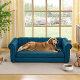 A golden retriever relaxes on a teal blue, tufted, rectangular elevated dog bed sofa in a bright room overlooking a garden.