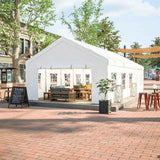 A white NatureScape Living Heavy Duty Party Tent with arched windows features an inviting outdoor lounge setup in a brick plaza.