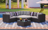 A NatureScape Living GO 7-piece outdoor wicker sofa set with beige cushions, striped pillows, and a coffee table on a deck.