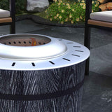 A NatureScape Living Smokeless Fire Pit with a silver top, visible flames, and a dark textured magnesium oxide base on a patio.