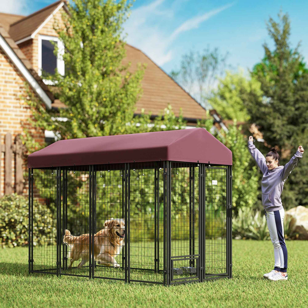 A golden retriever inside NatureScape Living's walk-in dog kennel with a maroon roof and rotating bowl holders on a green lawn.