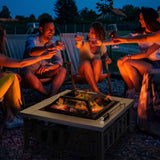 A happy group enjoys a NatureScape Living 34" Square Wood Burning Fire Pit outdoors at night, surrounded by glowing embers.