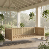 A TOPMAX Wood Swing Bed, featuring light wood and woven rattan, hangs on a serene porch surrounded by lush green plants.