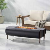 The VERNON Rectangle Fire Pit, a dark gray oval unit with a rectangular burner, flames, and wooden legs, rests on a patio.