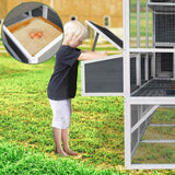 A child opens the grey nesting box of the NatureScape Living Walk-in Chicken Coop for 10 Chickens, showing eggs within, in a green backyard.