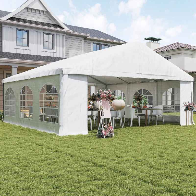 A white NatureScape Living Wedding Party Tent with sidewalls is set up on a green lawn, decorated with tables, chairs, and flowers for an event.