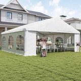 A white NatureScape Living Wedding Party Tent with sidewalls is set up on a green lawn, decorated with tables, chairs, and flowers for an event.