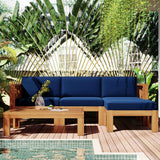 A TOPMAX 5-piece wood patio sectional with blue cushions and coffee table on a deck by a pool, surrounded by tropical plants.